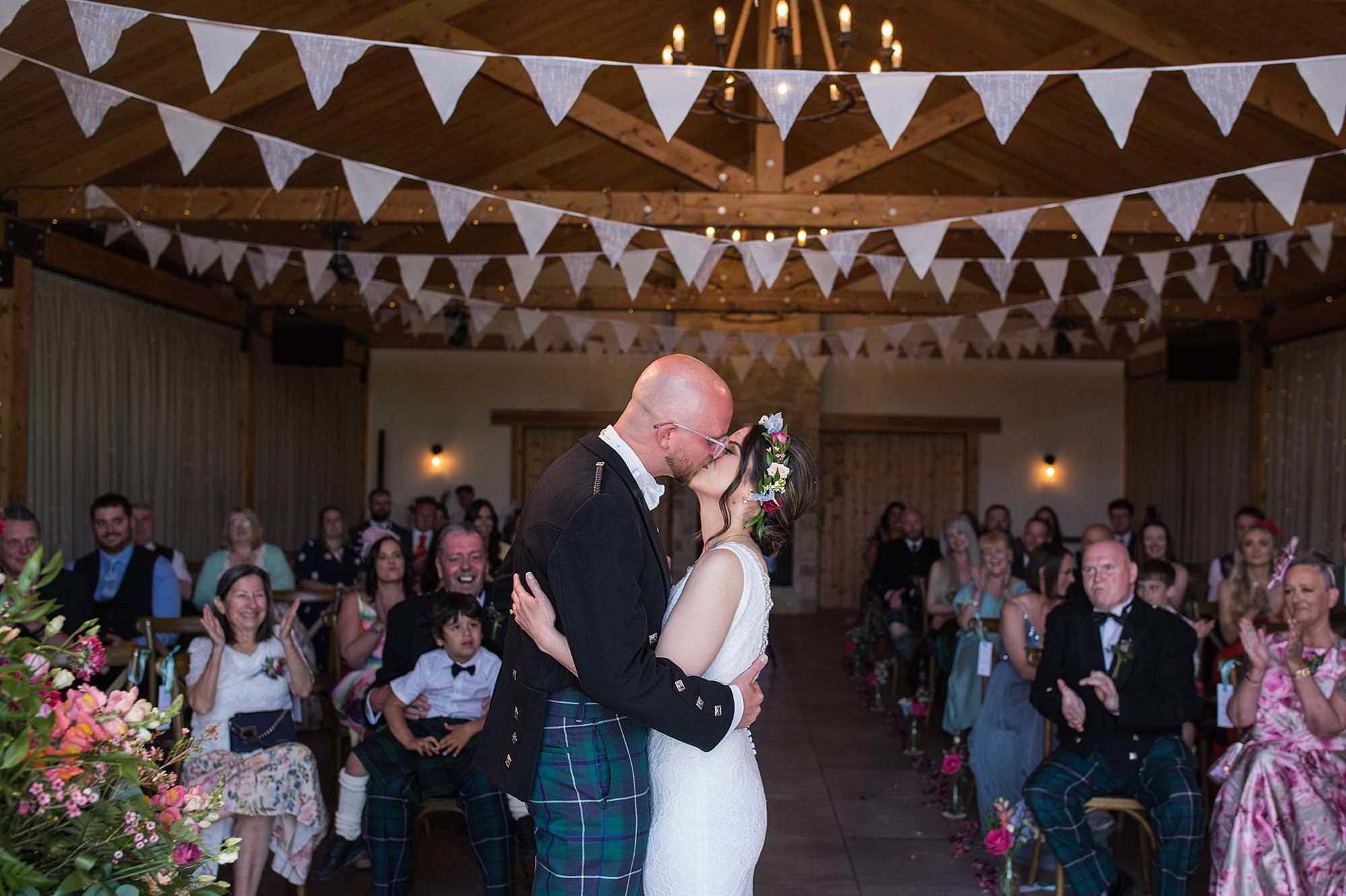 Bride and groom have first kiss during their wedding ceremony at Roodlea Barn